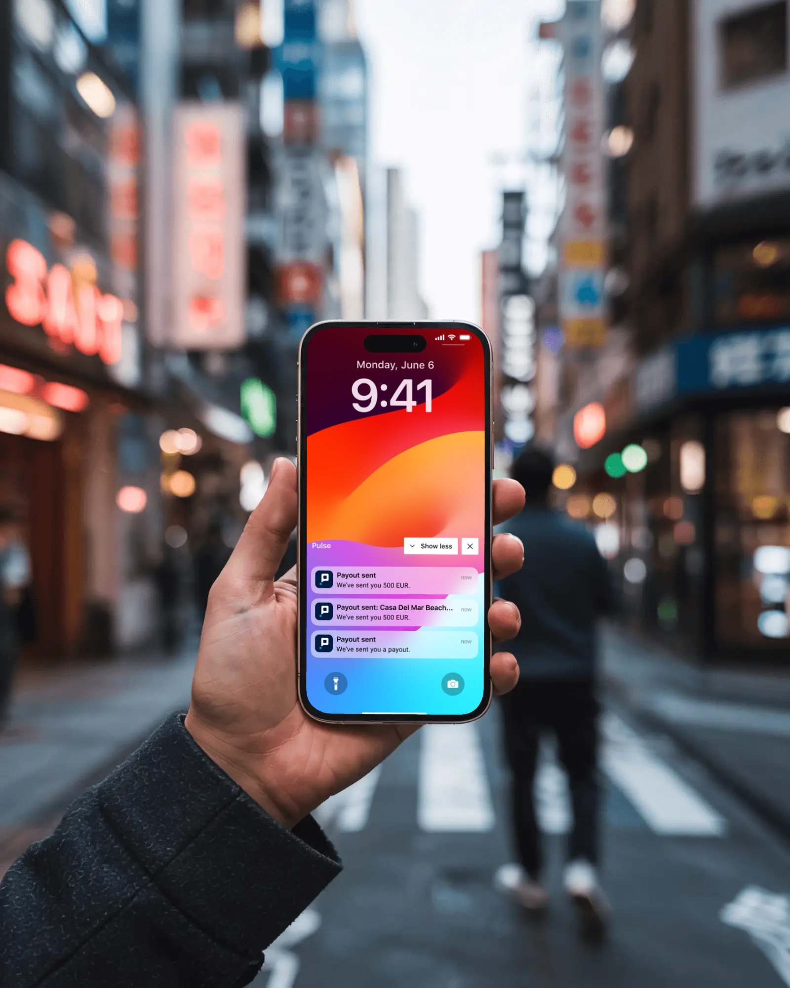 A person checking payout notifications on the Pulse app while holding a phone on a city street